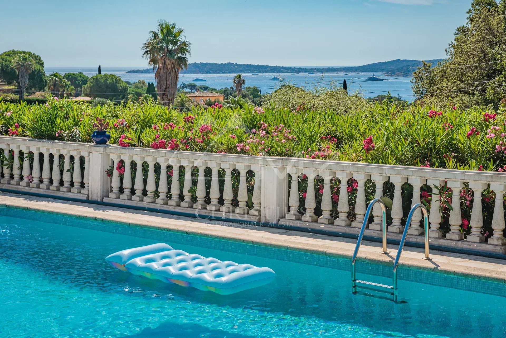 Villa provençale avec vue mer à Grimaud Vue sur la mer depuis une villa provençale avec piscine, entourée de fleurs à Grimaud.