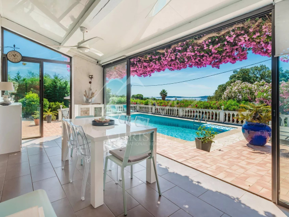 Intérieur lumineux d'une villa provençale avec vue sur piscine et jardin fleuri à Grimaud.