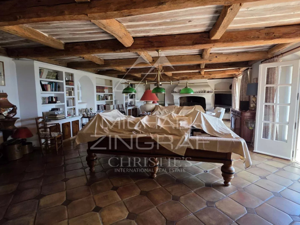 Intérieur d'une villa avec poutres en bois et mobilier traditionnel, vue sur un jardin.