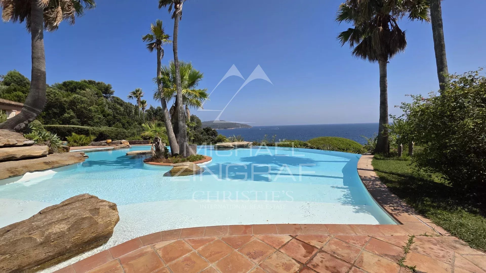 Vue de la piscine et du jardin d'une villa pieds dans l'eau à La Croix-Valmer, près de Saint-Tropez.