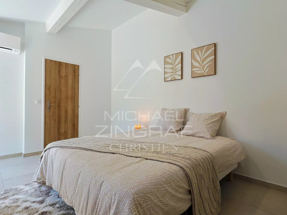 Chambre d'une villa en pierre rénovée, avec lit double et décor moderne.