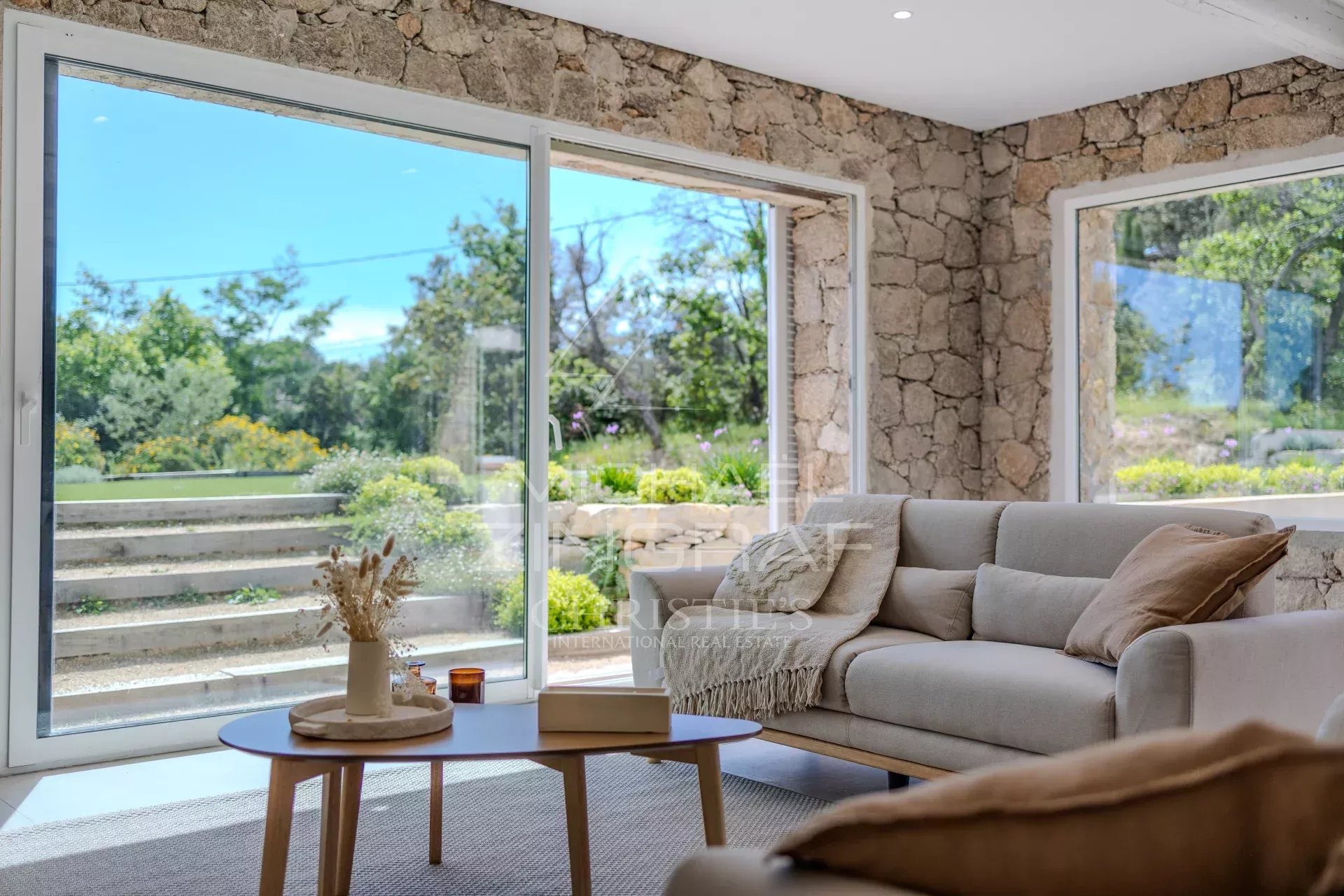 Intérieur d’une villa en pierre rénovée Intérieur d'une villa en pierre rénovée avec un salon lumineux et des fenêtres donnant sur le jardin.