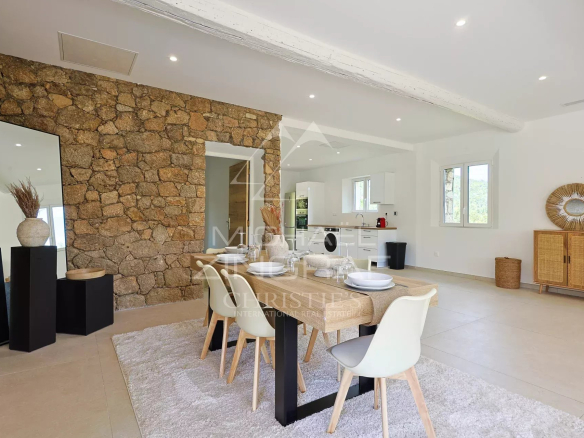 Intérieur d'une villa en pierre rénovée avec salle à manger moderne et cuisine ouverte.