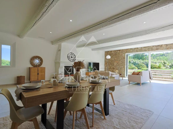 Intérieur d'une villa en pierre rénovée, avec salle à manger et vue sur le jardin.