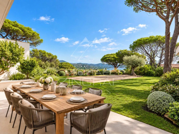 Terrace of a contemporary villa with wooden table and view of a landscaped garden in Sainte-Maxime.