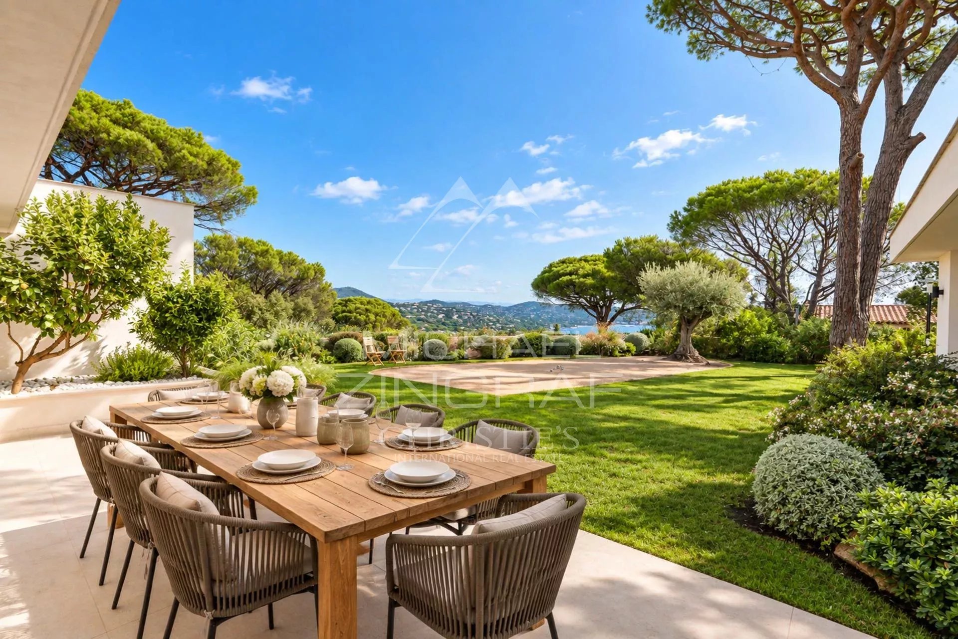 Terrace of a contemporary villa in Sainte-Maxime Terrace of a contemporary villa with wooden table and view of a landscaped garden in Sainte-Maxime.