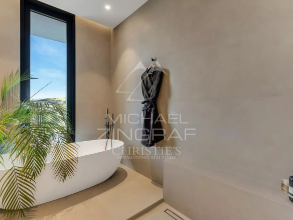 Modern bathroom with freestanding bathtub and view of the outside, decorated with plants.