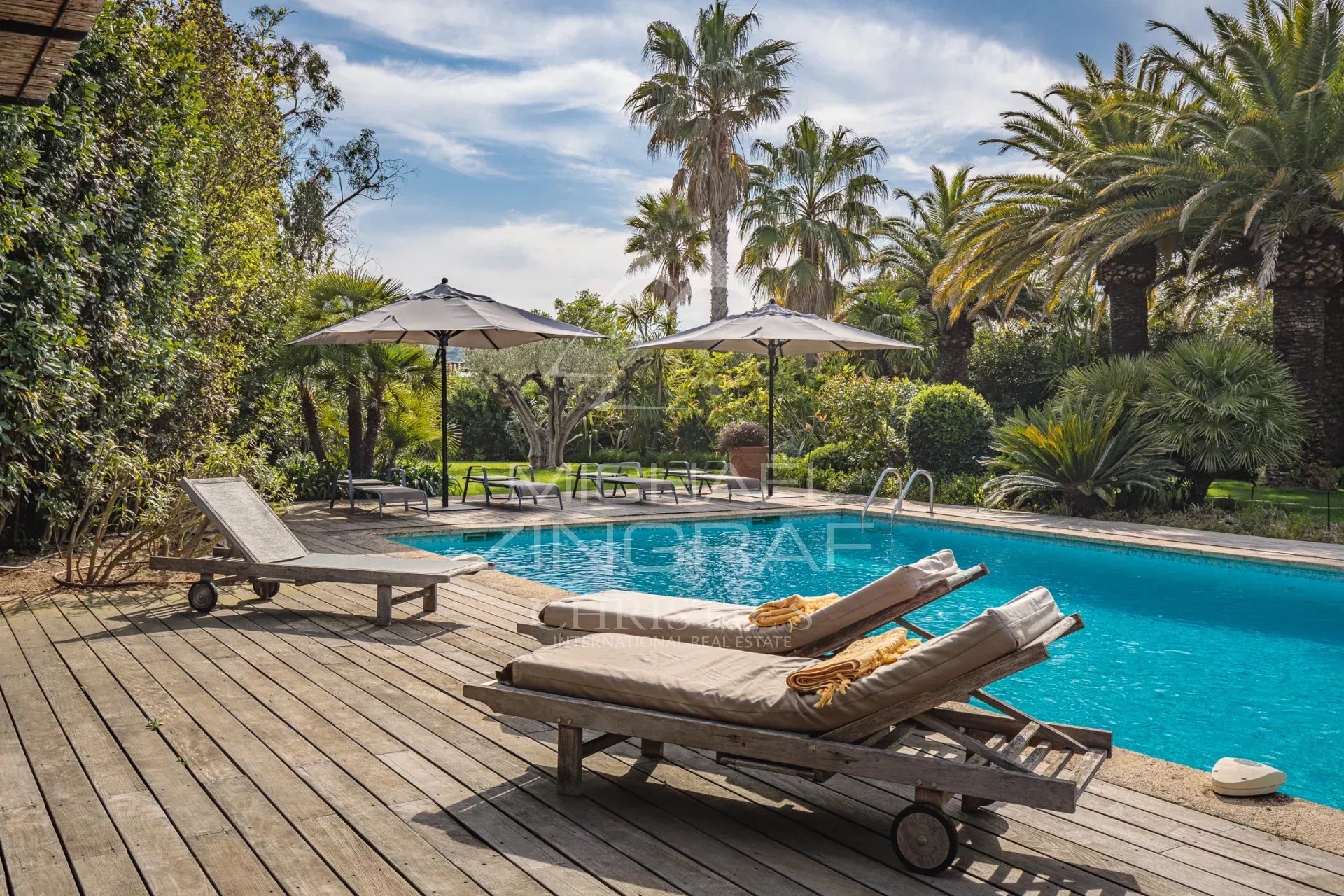 Provençal property with swimming pool in Saint-Tropez Swimming pool surrounded by palm trees and wooden sun loungers in a Provençal property in Saint-Tropez.