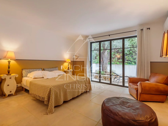 Room in a Provençal property in Saint-Tropez, with bed, armchair and access to an outdoor area.