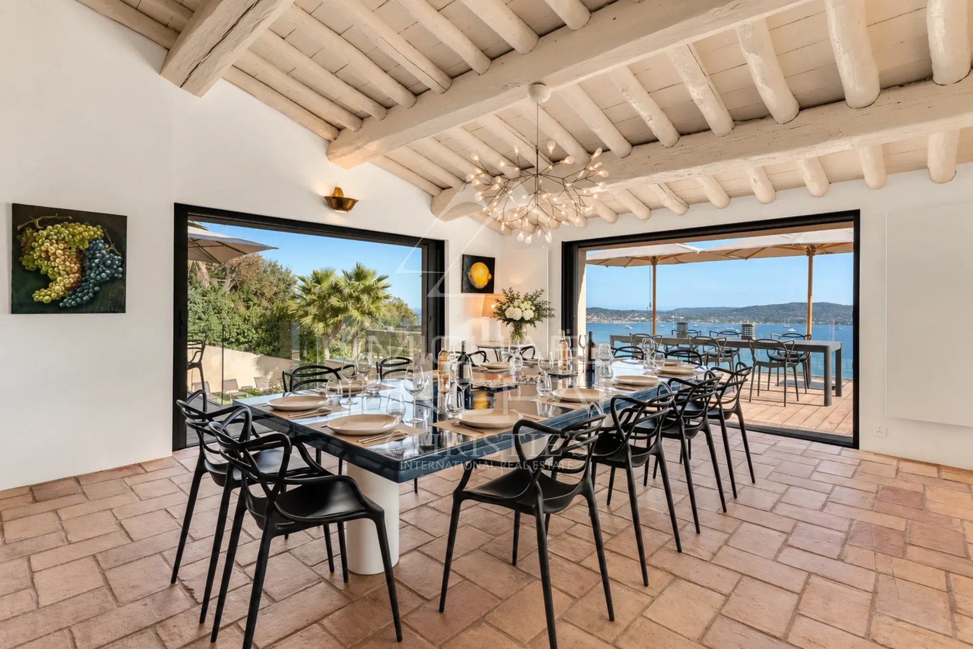 Dining room of Villa Levante Modern dining room with views of the Gulf of Saint-Tropez, large windows and elegant decor.