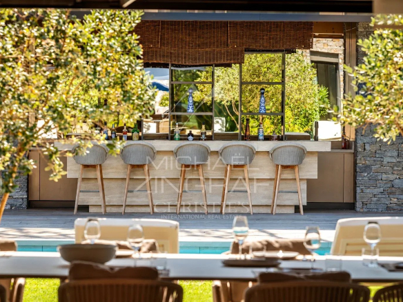 Outdoor bar at the villa with chairs and a view of the pool.