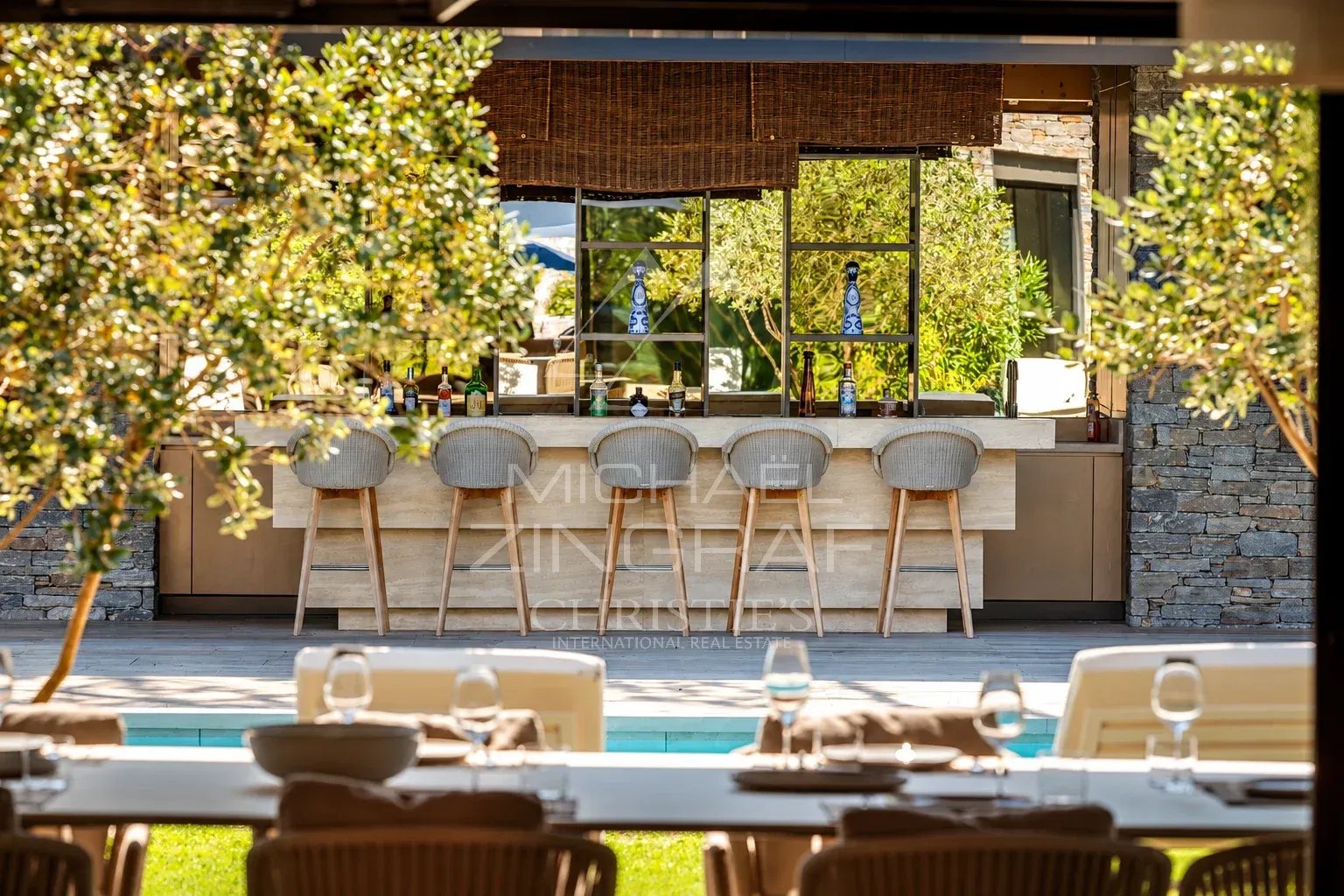 Outdoor bar at the villa with chairs and a view of the pool.