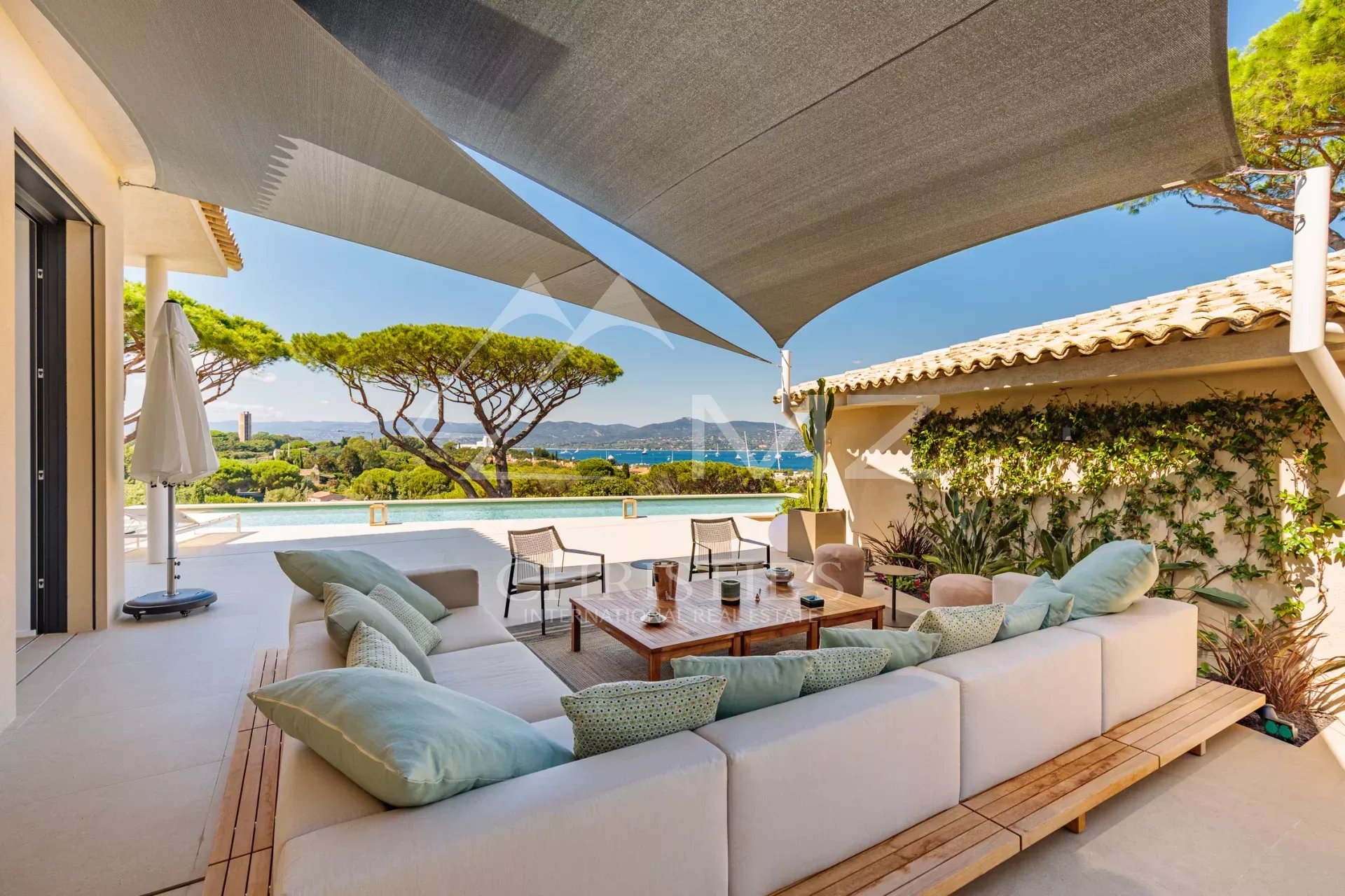Villa contemporaine à Saint-Tropez Terrasse d'une villa contemporaine à Saint-Tropez avec vue sur la mer et des arbres en arrière-plan.