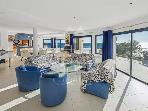 Intérieur d'une villa moderne avec vue sur la mer, mobilier contemporain et grandes baies vitrées.