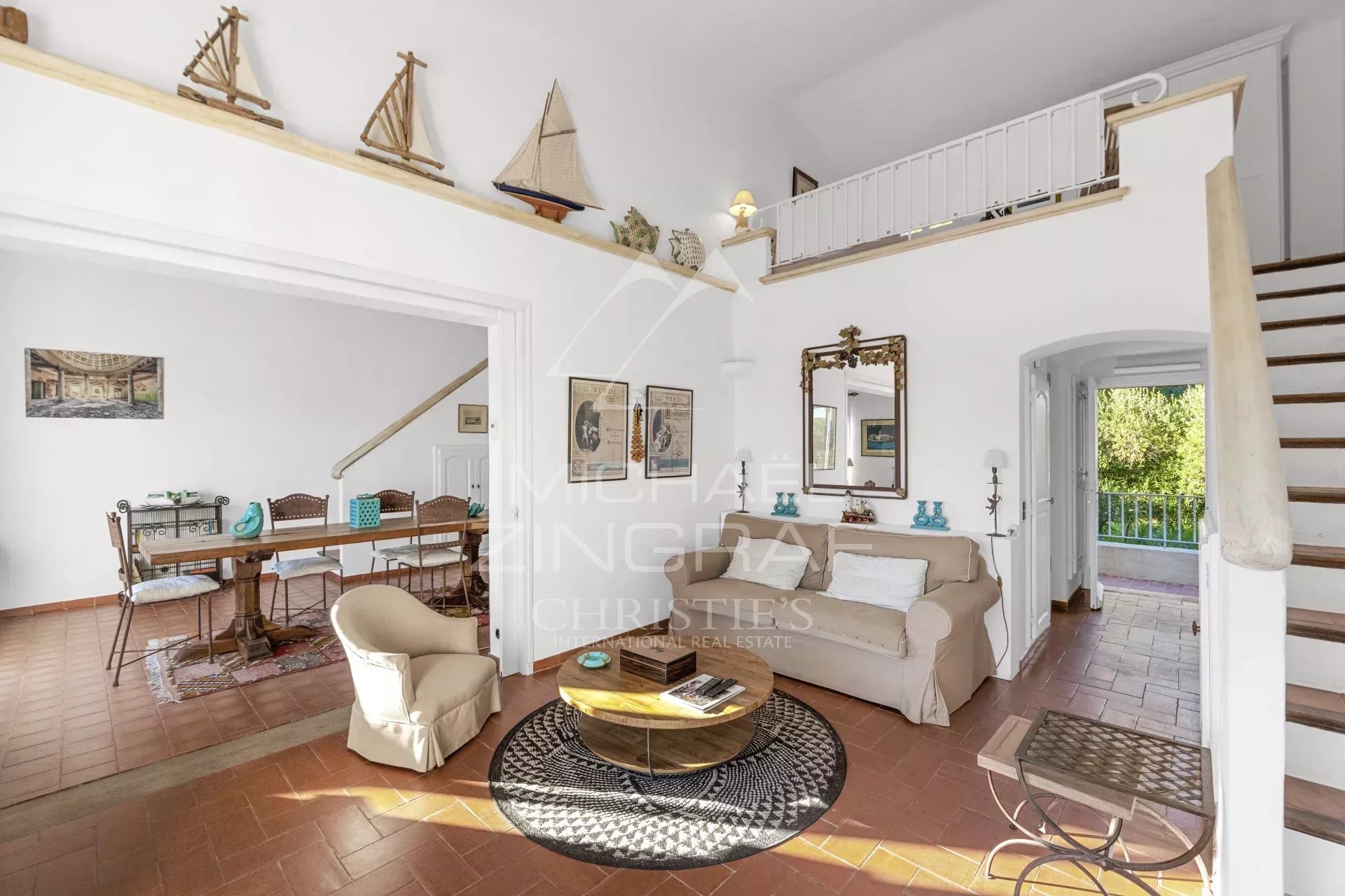Intérieur d’un mazet à Ramatuelle Intérieur d'un salon lumineux avec un coin repas et un escalier, dans un mazet à Ramatuelle.
