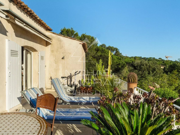 Terrasse ensoleillée avec chaises longues et plantes, vue sur la verdure à Ramatuelle.