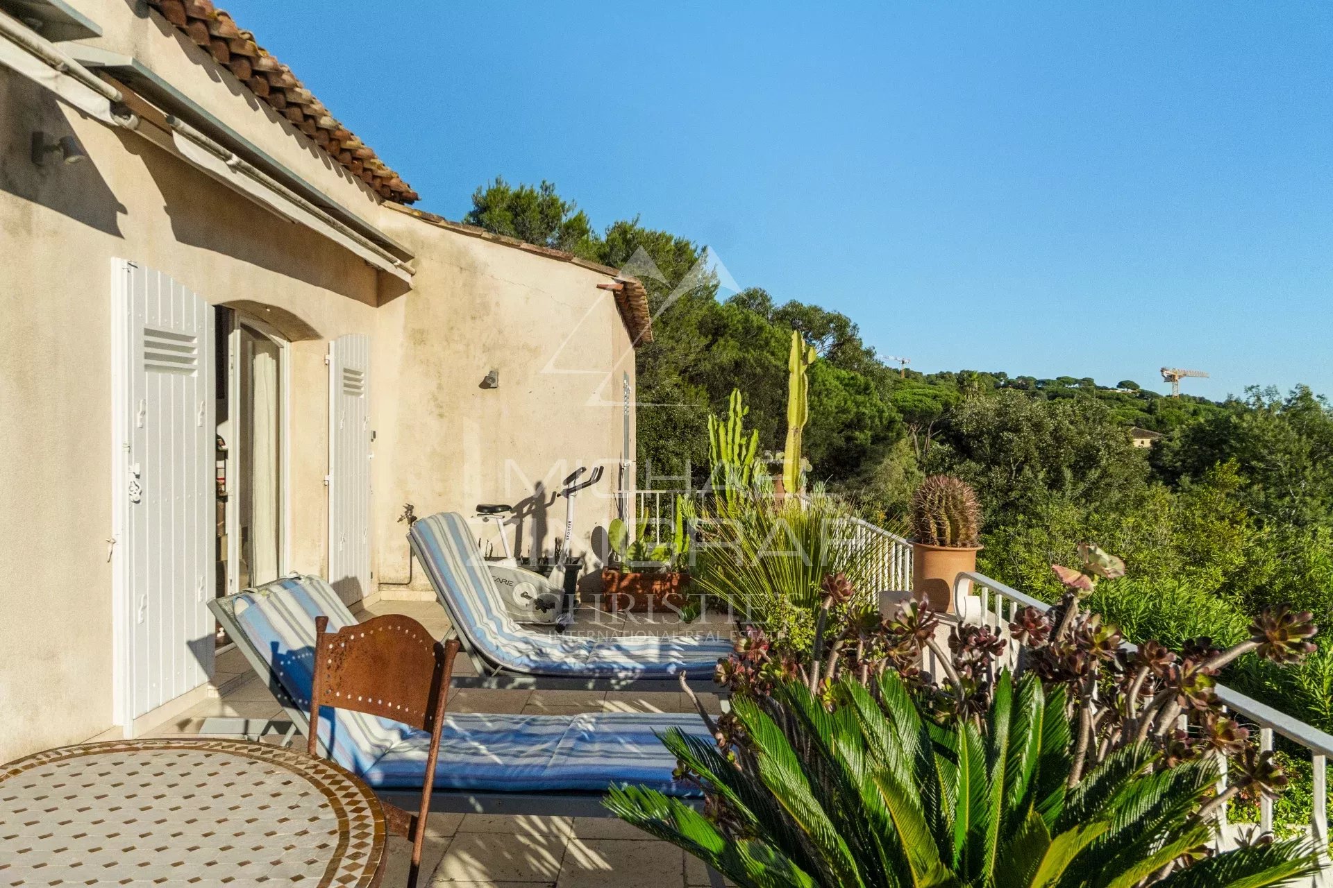 Terrasse de mazets à Ramatuelle Terrasse ensoleillée avec chaises longues et plantes, vue sur la verdure à Ramatuelle.