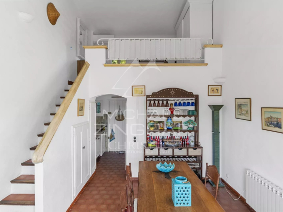 Intérieur d'un mazet à Ramatuelle avec une table en bois et un escalier menant à l'étage.