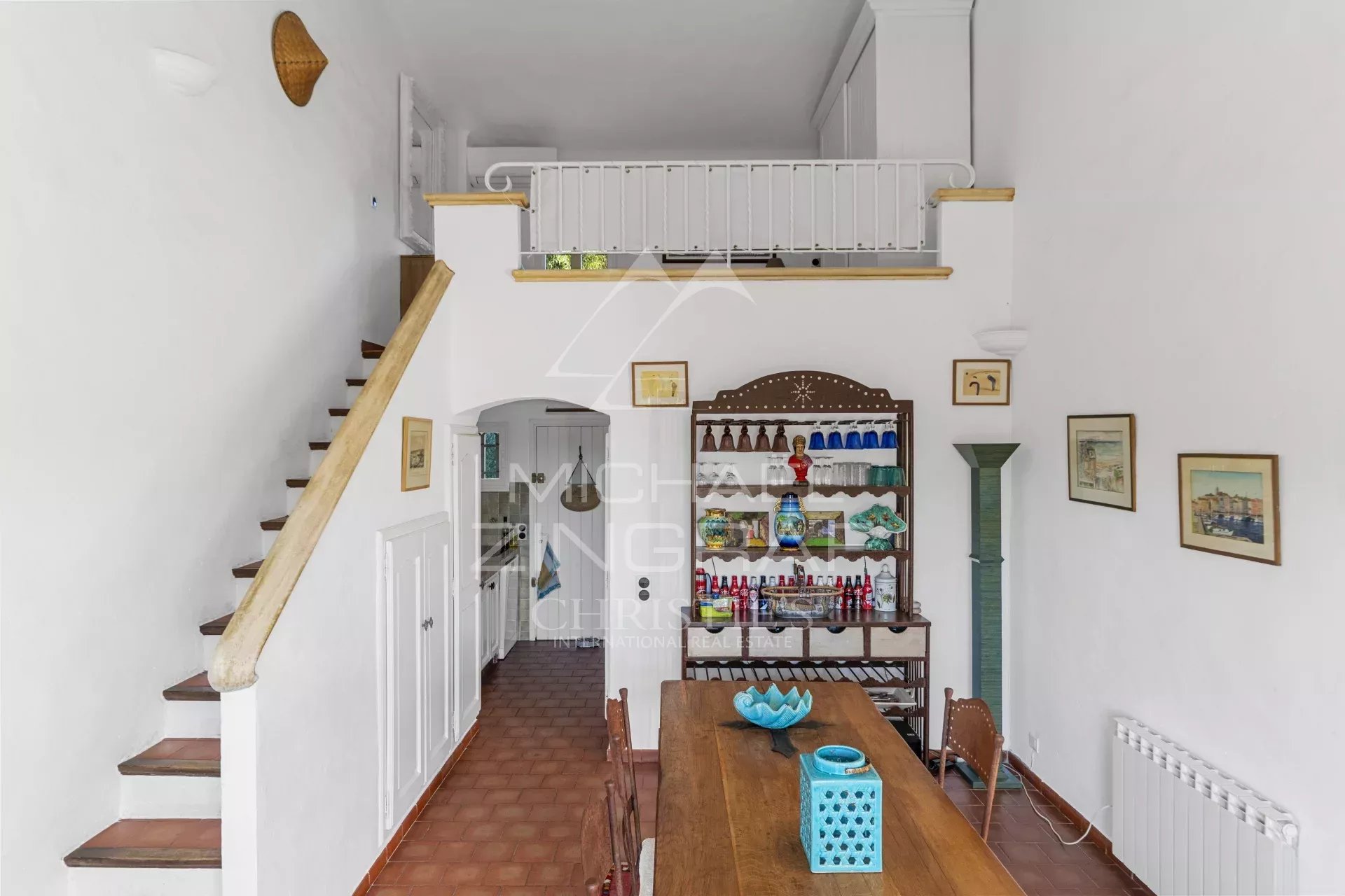 Intérieur d’un mazet à Ramatuelle Intérieur d'un mazet à Ramatuelle avec une table en bois et un escalier menant à l'étage.