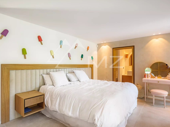 Chambre lumineuse avec lit double, décoration colorée et mobilier moderne dans une villa récente.