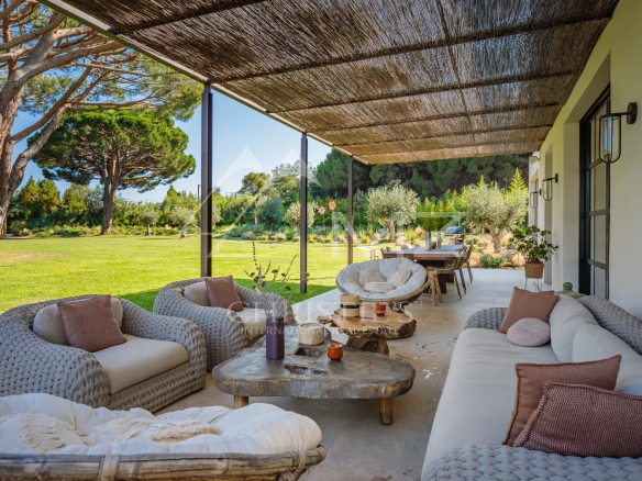 Terrasse d'une villa neuve avec mobilier confortable et vue sur un parc paysager à Ramatuelle.