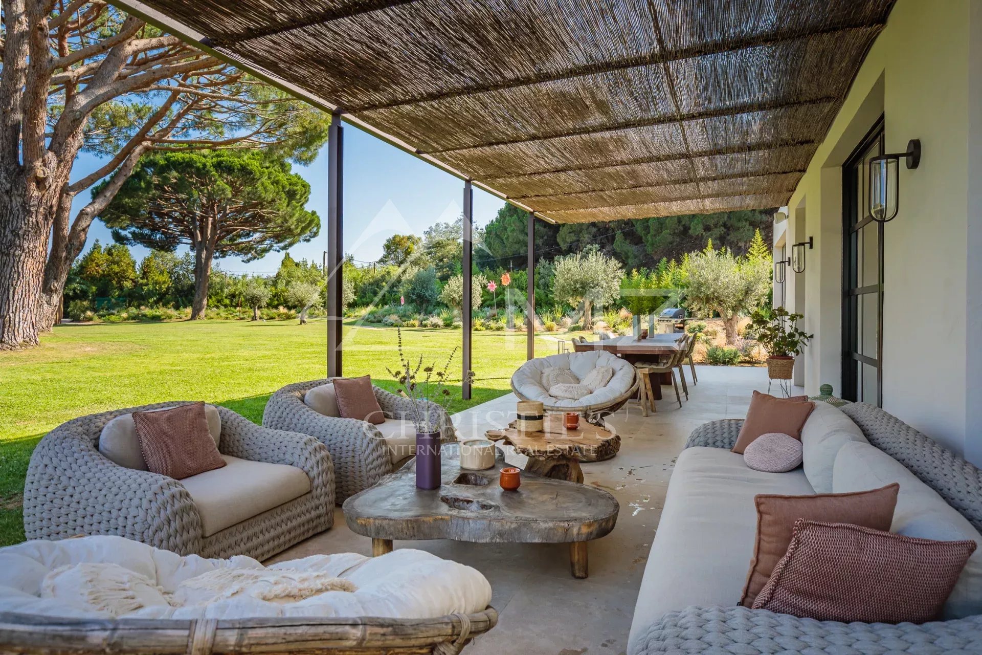 Terrasse de la Villa Shesh à Ramatuelle Terrasse d'une villa neuve avec mobilier confortable et vue sur un parc paysager à Ramatuelle.