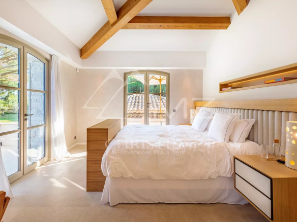 Chambre lumineuse d'une villa neuve à Ramatuelle avec lit double et décoration moderne.