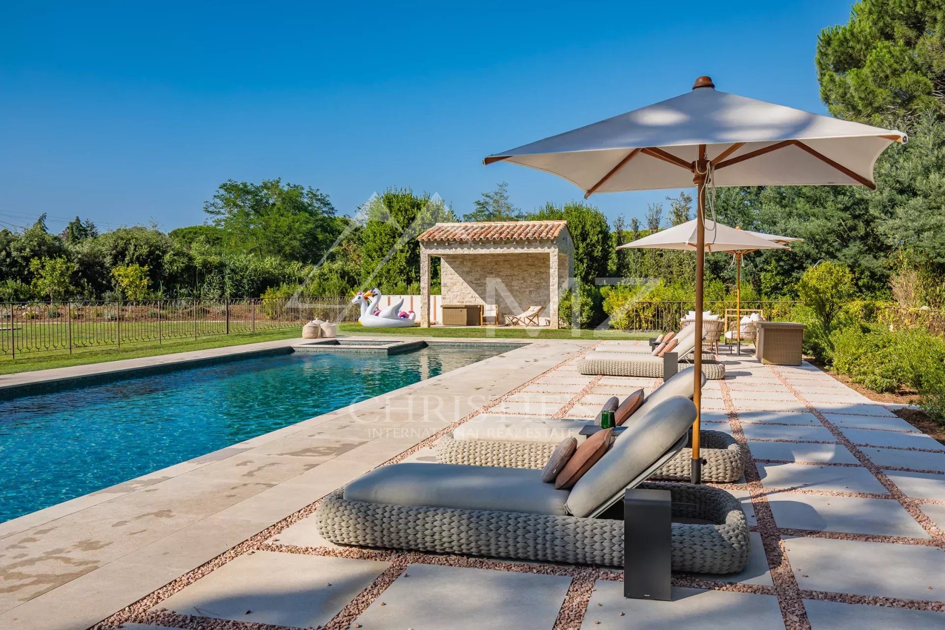 Villa Shesh à Ramatuelle Piscine avec chaises longues et parasols dans un parc paysager.