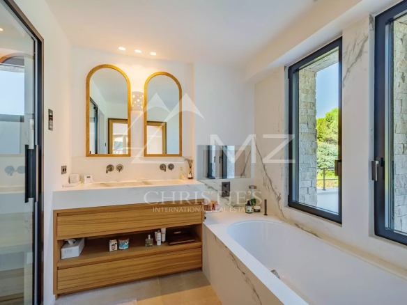 Salle de bain moderne avec baignoire et double vasque dans une villa récente.
