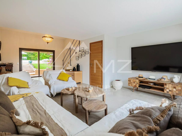 Intérieur d'une villa moderne avec salon lumineux, télévision et mobilier confortable.