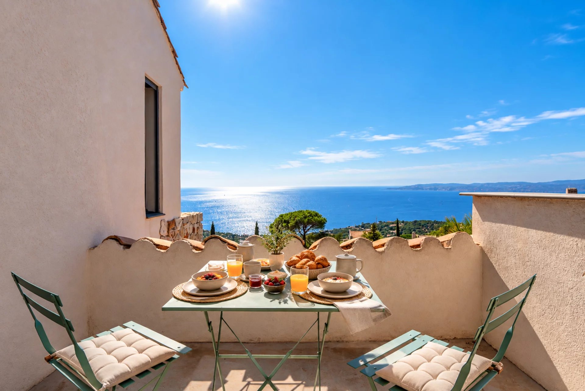 Terrasse avec vue panoramique sur la mer Terrasse avec vue sur la mer, table dressée avec petits-déjeuners, ciel bleu et mer en arrière-plan.