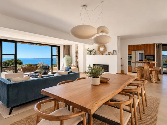 Intérieur d'une villa moderne avec vue sur la mer, salon et salle à manger en bois.