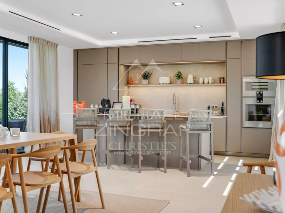 Modern interior of a villa with open kitchen and bar, overlooking the outside.