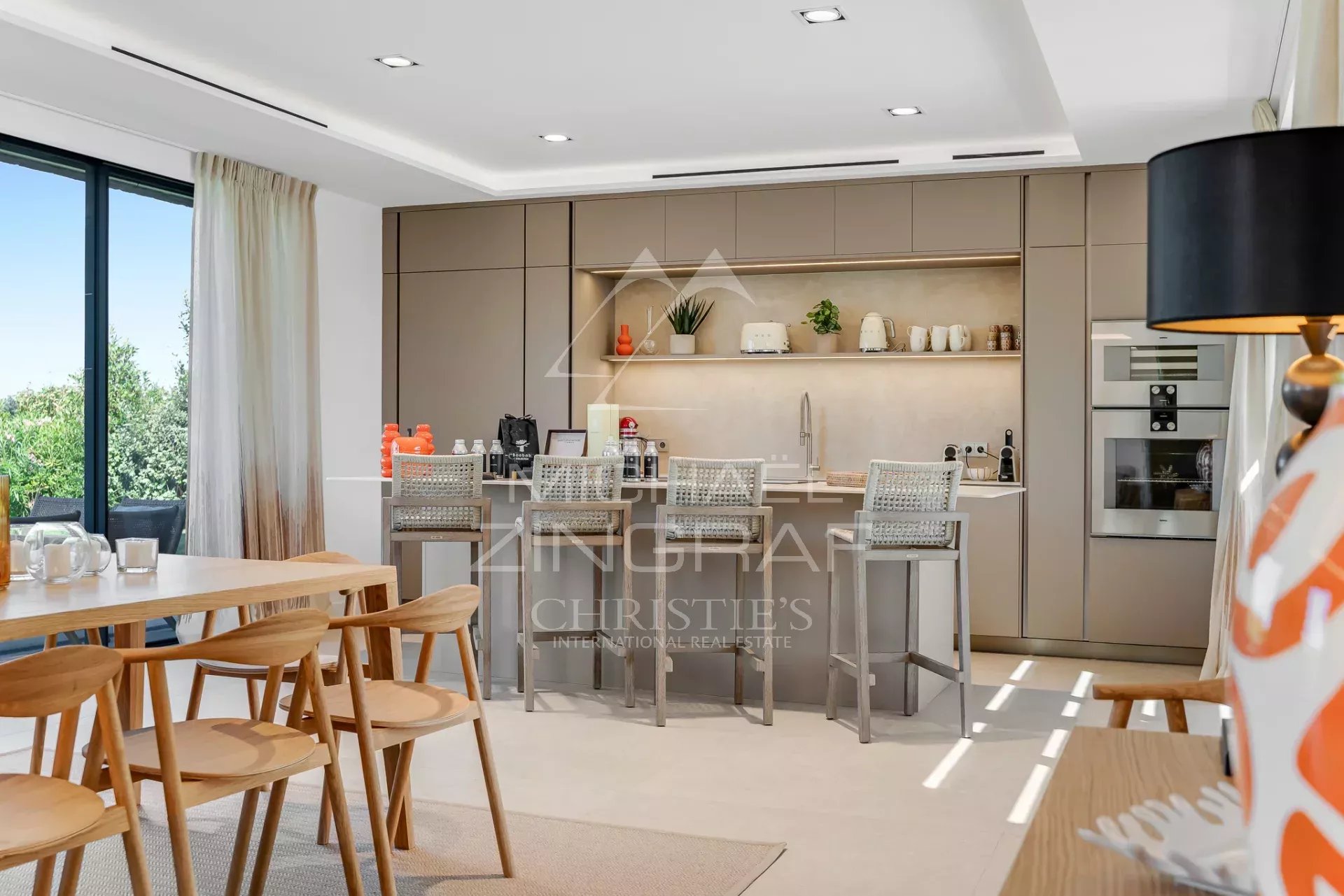 Contemporary kitchen in a villa in Saint-Tropez Modern interior of a villa with open kitchen and bar, overlooking the outside.
