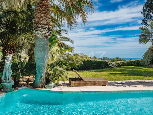 Vue de la piscine entourée de palmiers et d'un jardin verdoyant à Grimaud, Golfe de Saint-Tropez.