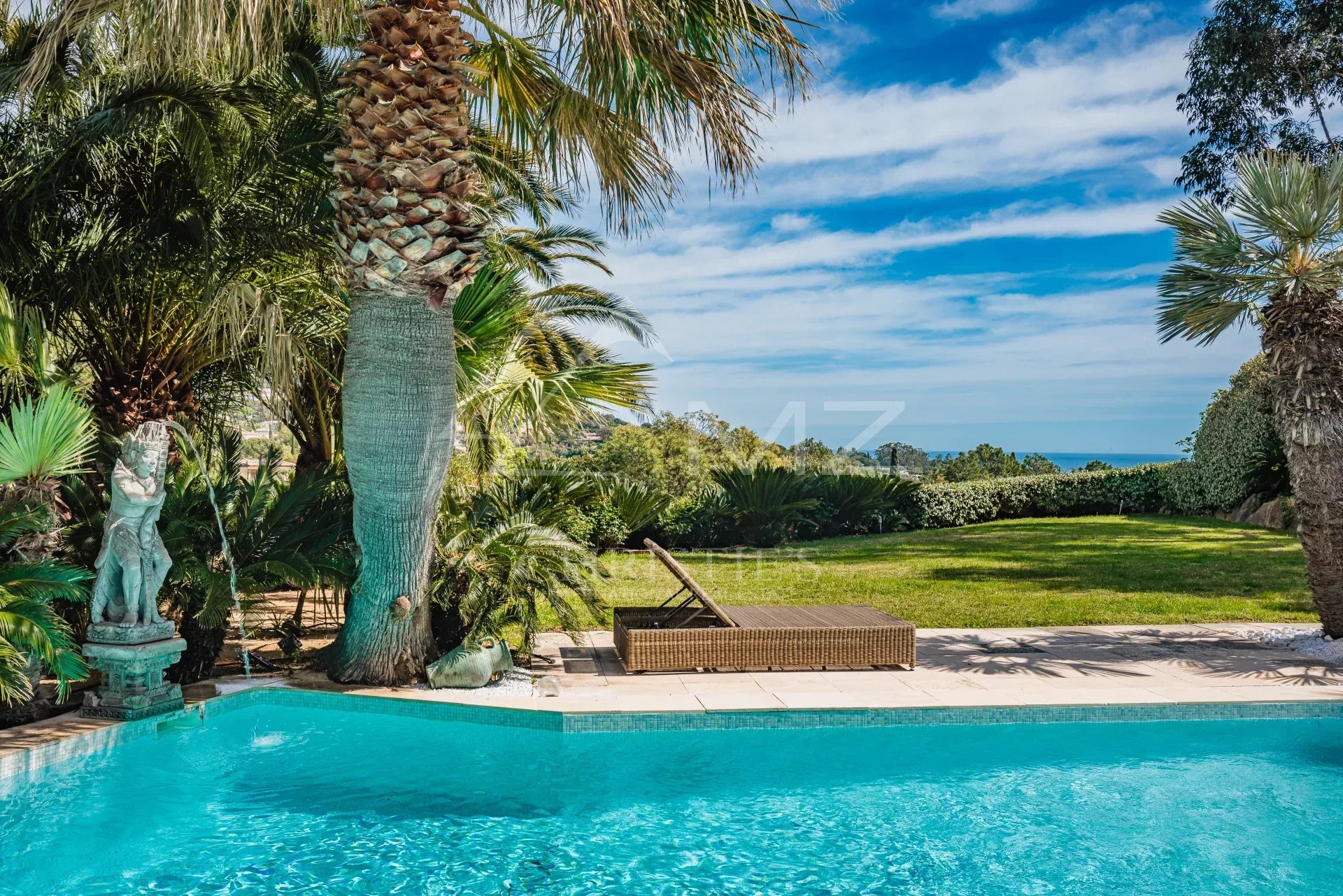 Villa avec piscine à Grimaud Vue de la piscine entourée de palmiers et d'un jardin verdoyant à Grimaud, Golfe de Saint-Tropez.