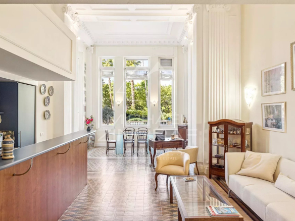 Bright living room with white ornate columns, large windows, and a glass coffee table. (Informative interior photo)