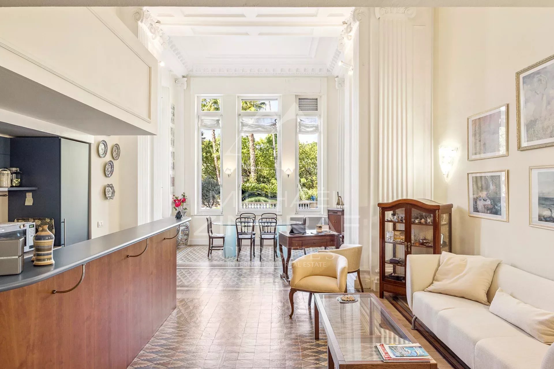 Bright living room with white ornate columns, large windows, and a glass coffee table. (Informative interior photo)