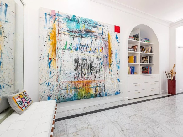 Interior of a stylish apartment with a large, colorful painting and modern furniture.