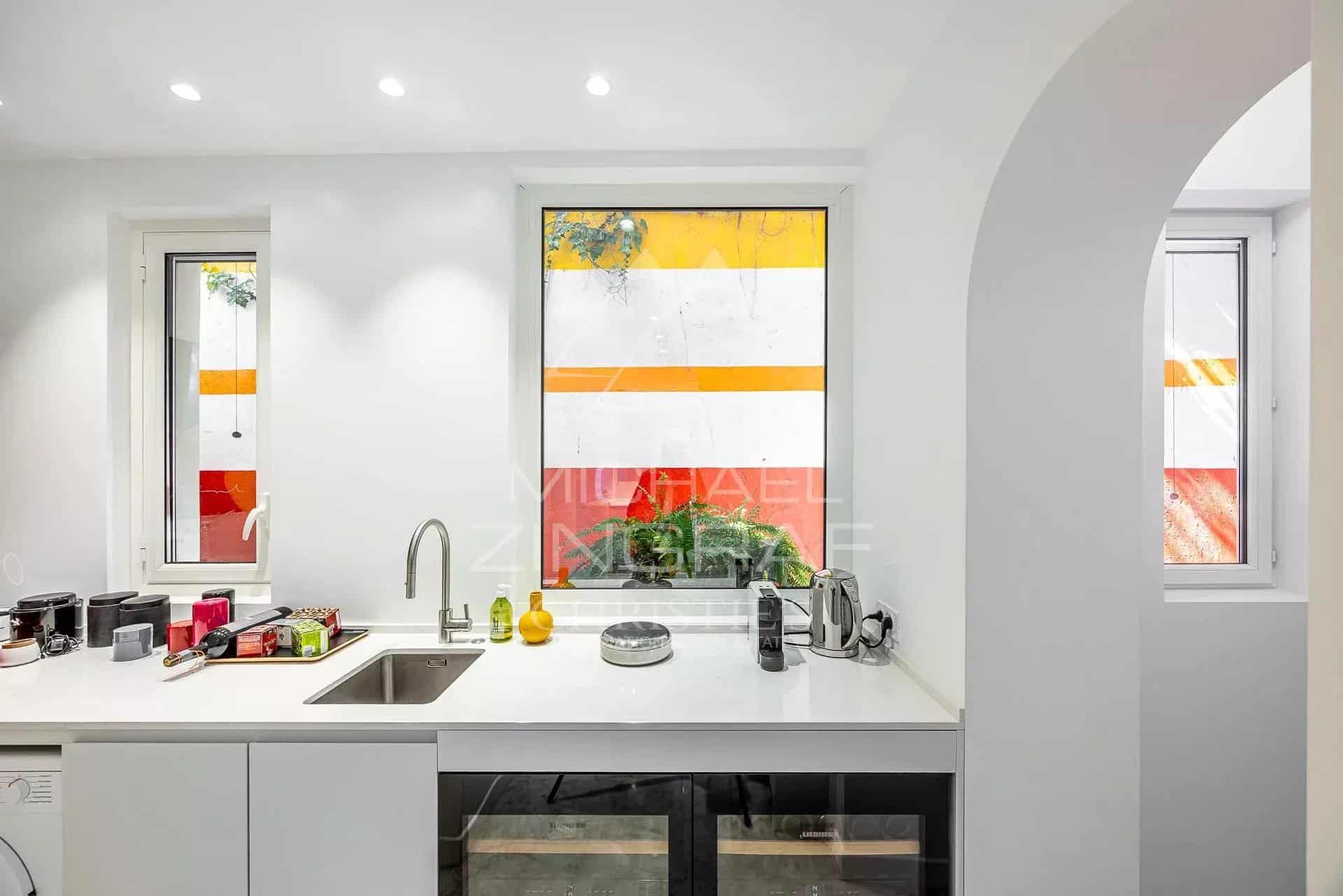 Kitchen of an apartment in Menton Modern kitchen with windows overlooking colorful walls.