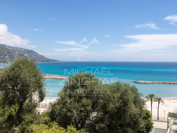 Sea view from an apartment in Menton, with trees and a beach in the background.