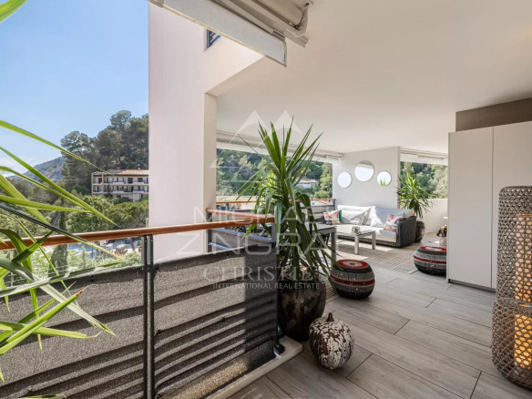 Terrasse d'un appartement moderne à Èze avec mobilier extérieur et vue sur la nature environnante.