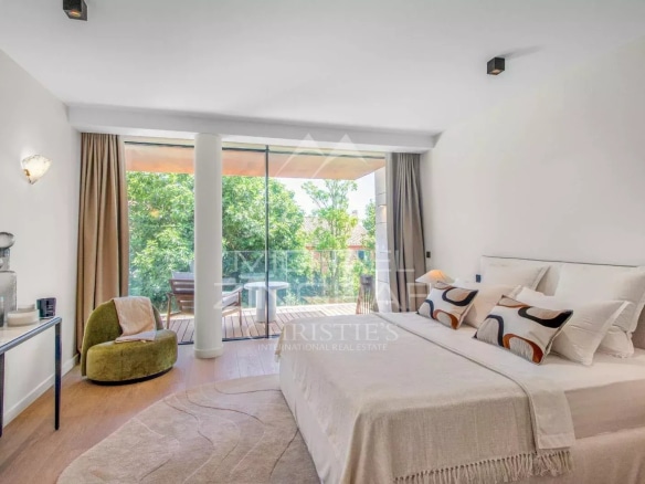 Modern room with bed, armchair and access to a balcony in a contemporary villa.