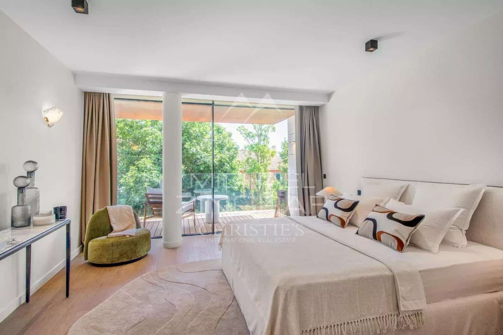 Modern room with bed, armchair and access to a balcony in a contemporary villa.