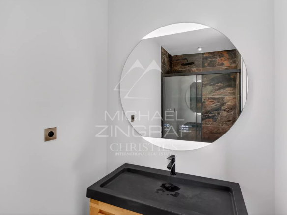Salle de bain moderne avec miroir rond et lavabo en pierre.