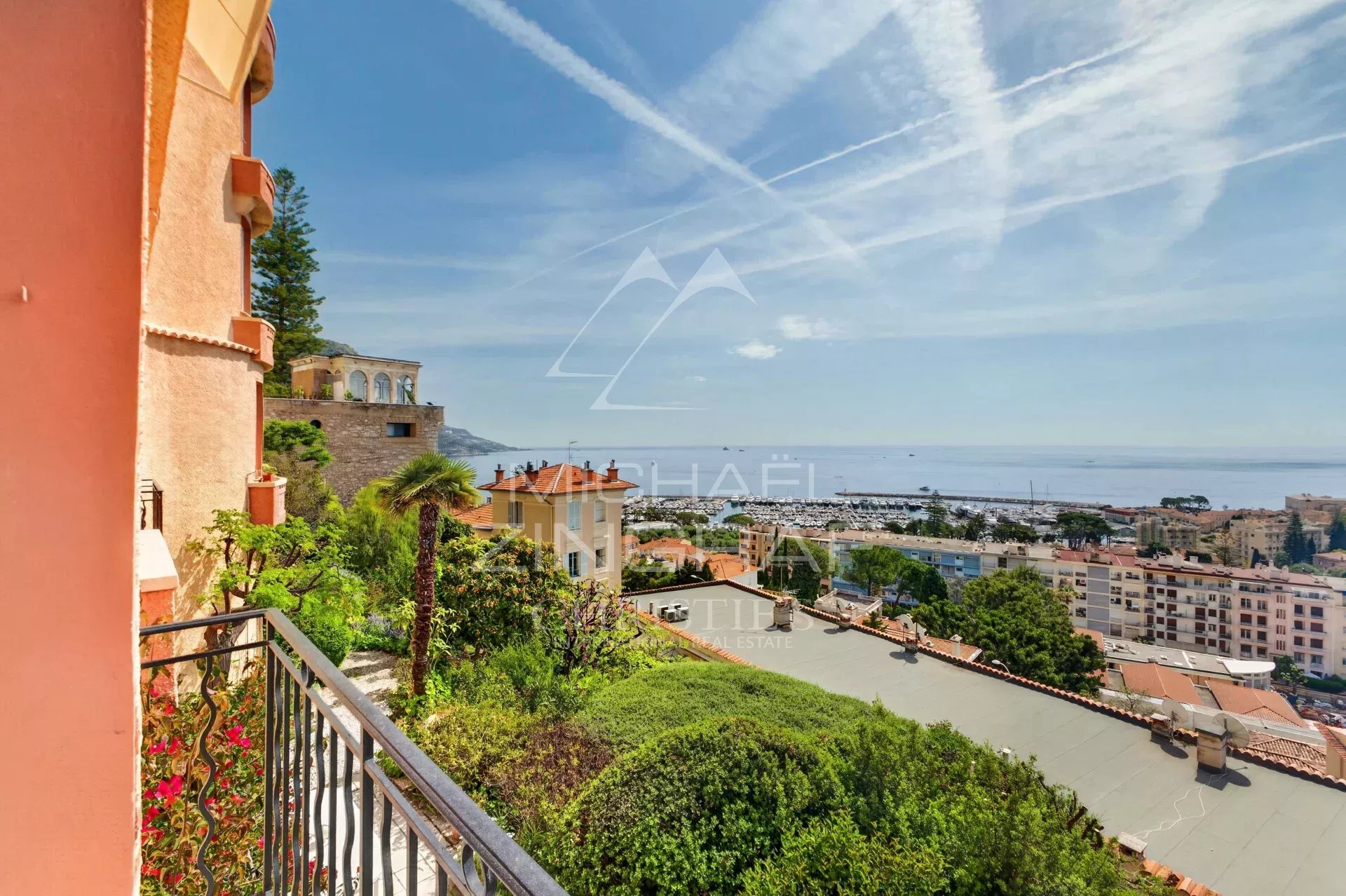 Appartement d’exception à Beaulieu-sur-Mer Vue panoramique sur la mer depuis un appartement à Beaulieu-sur-Mer, avec jardins et bâtiments environnants.