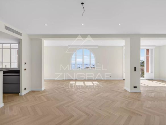 Intérieur d'un appartement rénové à Beaulieu-sur-Mer avec vue mer, parquet en bois et grandes fenêtres.