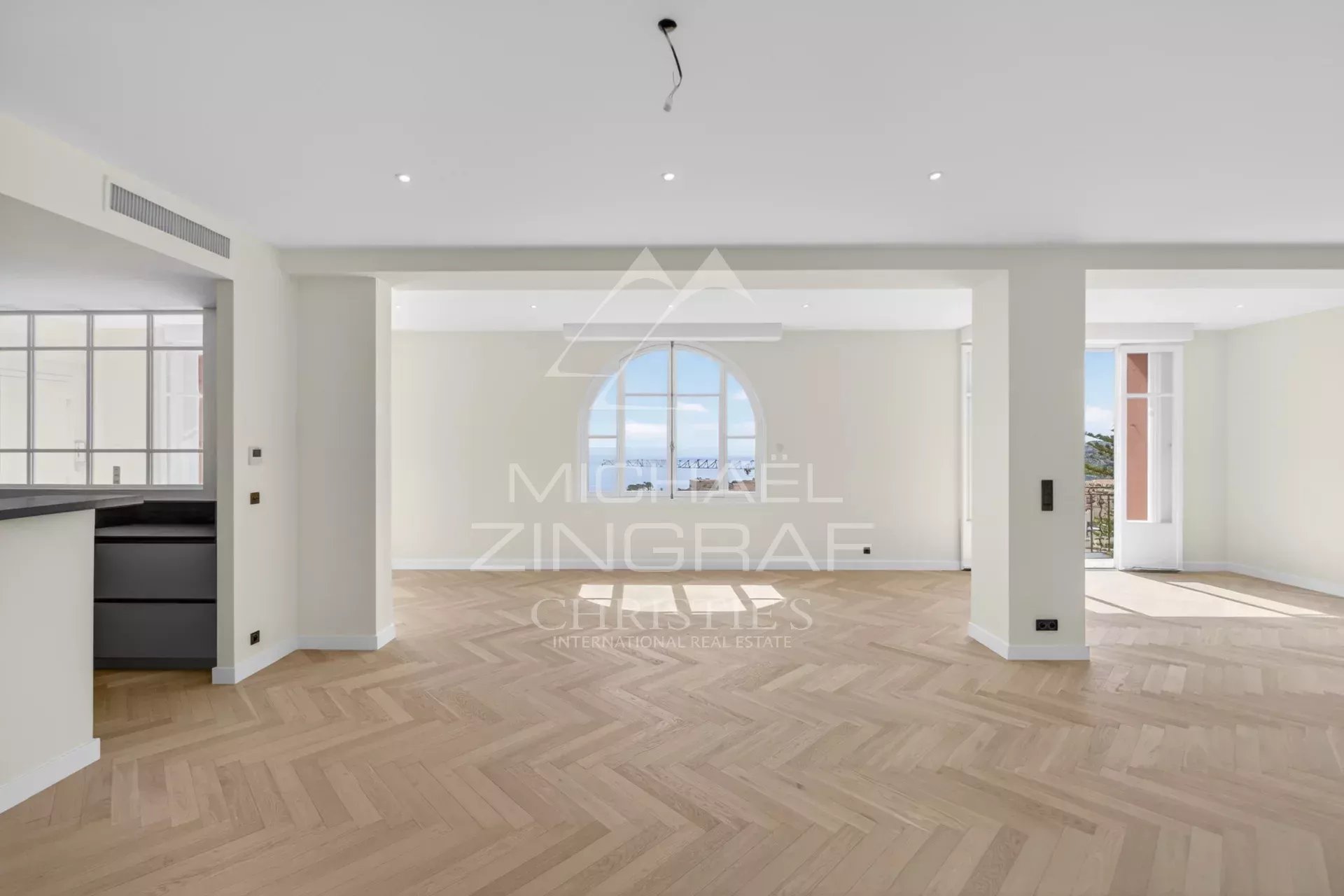 Appartement d’exception à Beaulieu-sur-Mer Intérieur d'un appartement rénové à Beaulieu-sur-Mer avec vue mer, parquet en bois et grandes fenêtres.