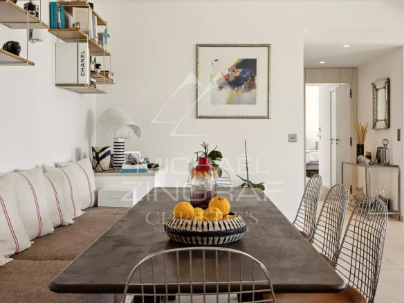 Intérieur d'un appartement moderne à Èze avec une grande table à manger et des coussins décoratifs.