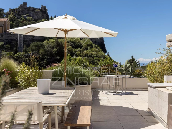 Terrasse spacieuse d'un appartement à Èze avec vue sur le village et la mer Méditerranée.